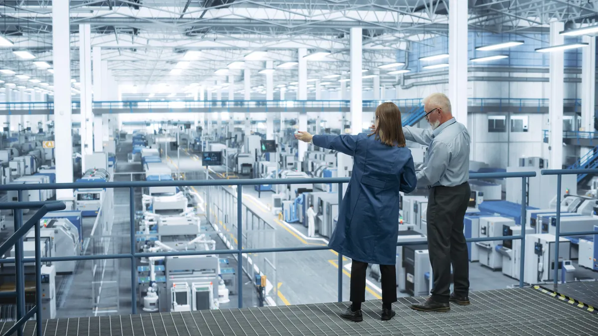 Engineers stand on a platform looking out at a factory.