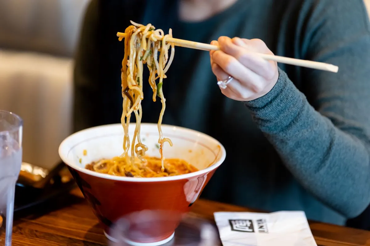 A photograph of a person eating ramen from Jinya Ramen Bar