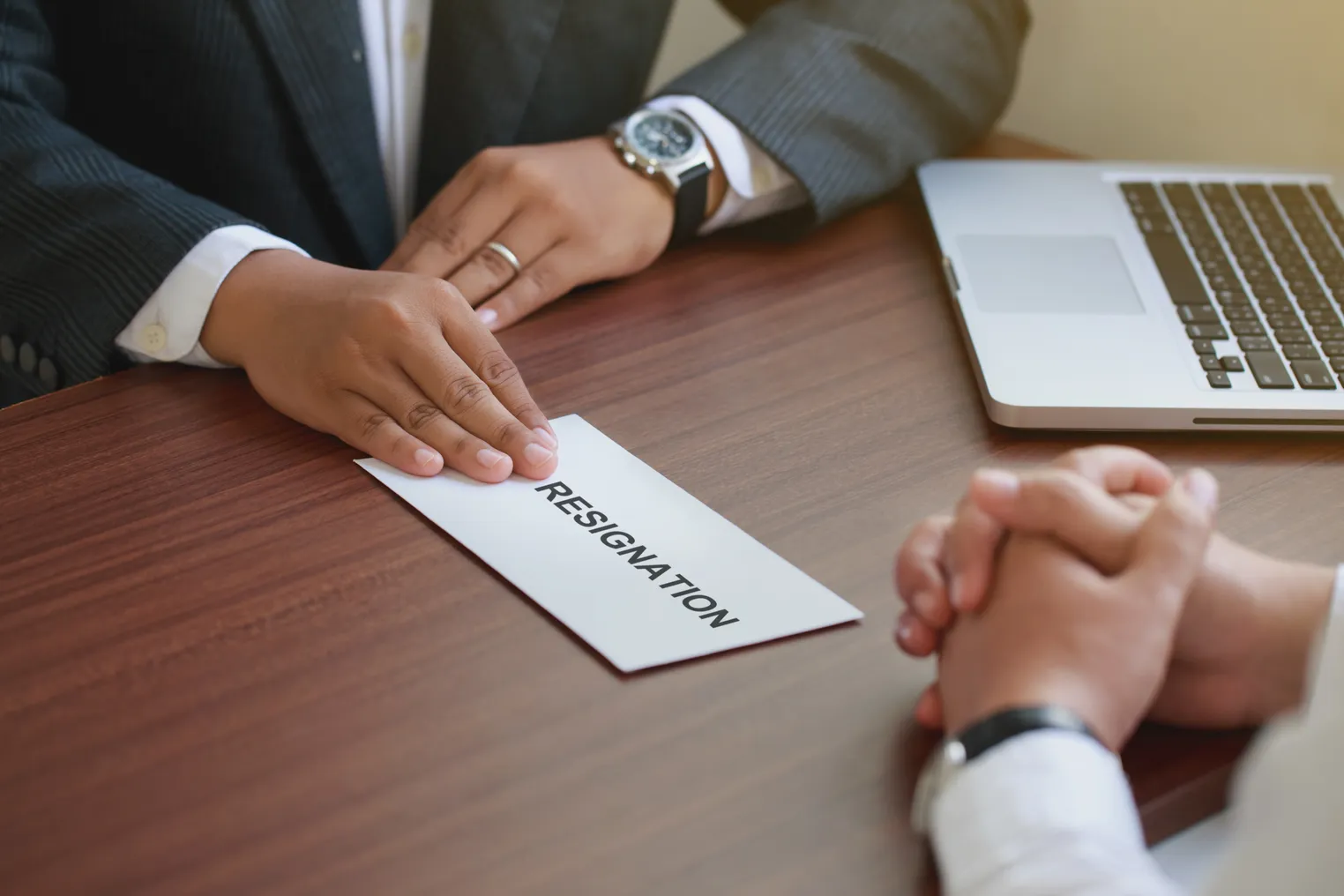 Hand of employer receiving a resignation letter from an employee.