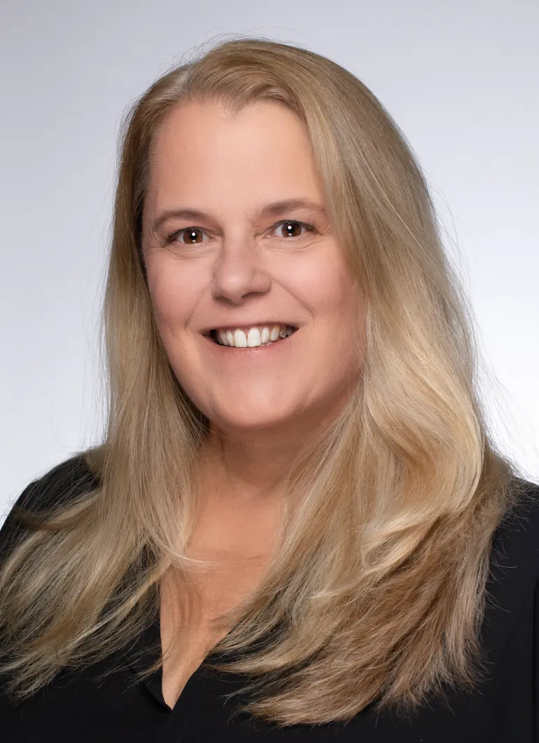A headshot shows a woman executive with long blonde hair in a black shirt.