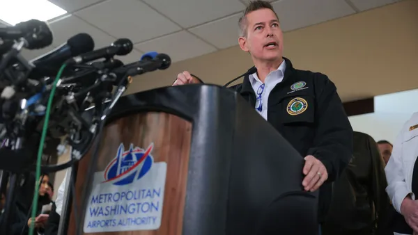 A man with silver hair speaks at a podium.