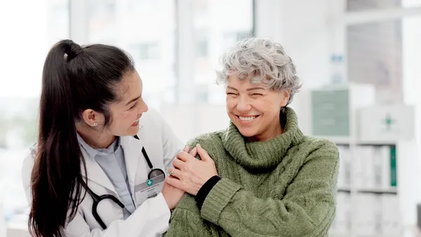 A woman converses with an older woman, both displaying attentive body language and expressions of interest in the dialogue.