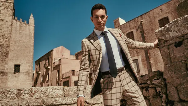 Person wearing a suit outside with a city backdrop.