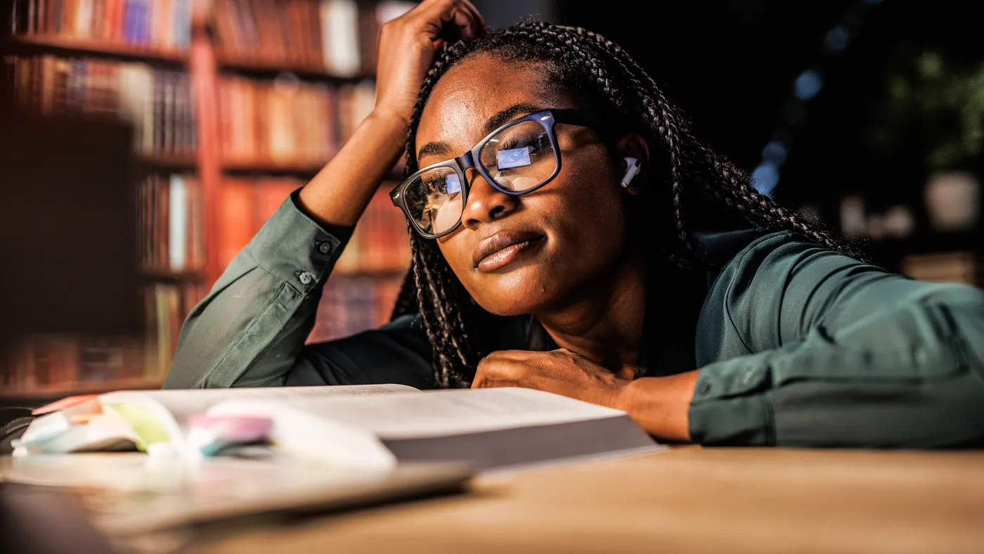 A young college student looks at a textbook in a library.