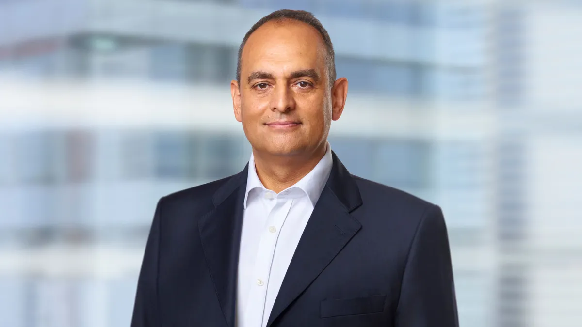 A person in business attire looks straight ahead.