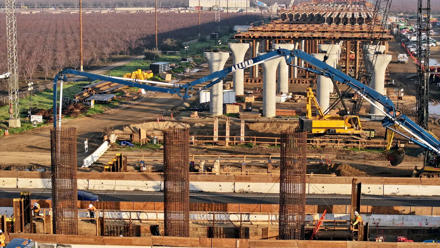 Aerial view of pilings and workers constructing a large viaduct.