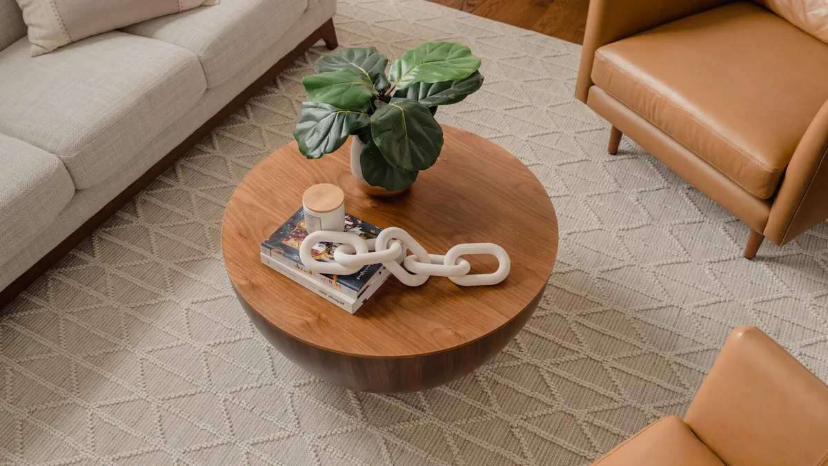 A cream colored textured rug sits under warm leather seats and a coffee table