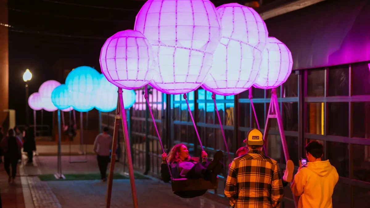 Visitors to the 2022 Georgetown GLOW light enjoy a swing, part of an interactive light display.