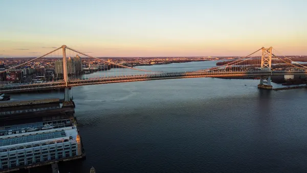 A wide shot of a bridge going over water at sunset.