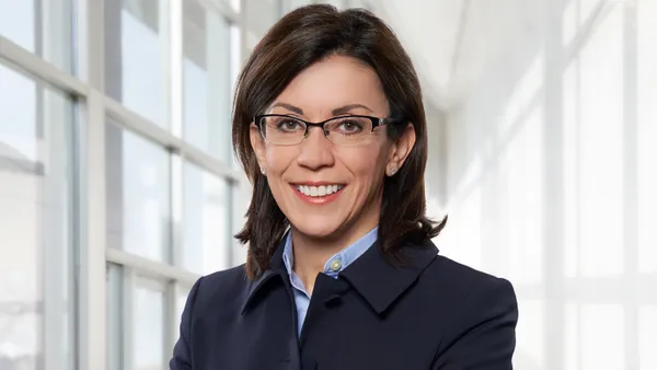 A headshot of Mojdeh Paul against with a window and white wall in the background.