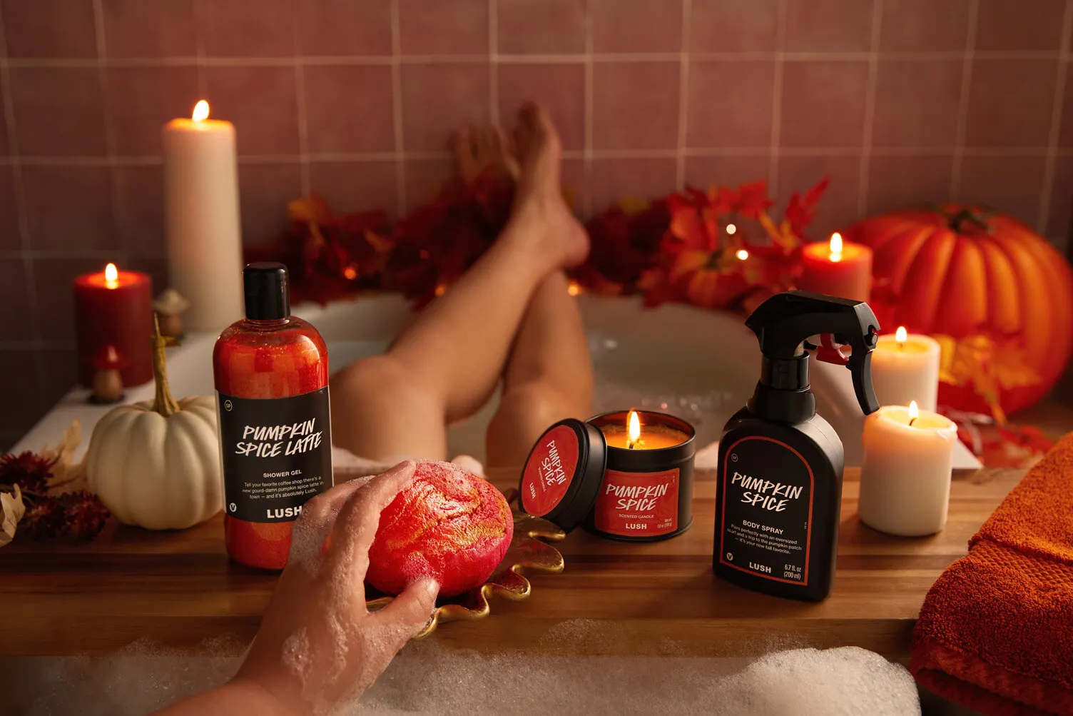 A person&#x27;s legs inside a candle lit bathtub with orange bath products