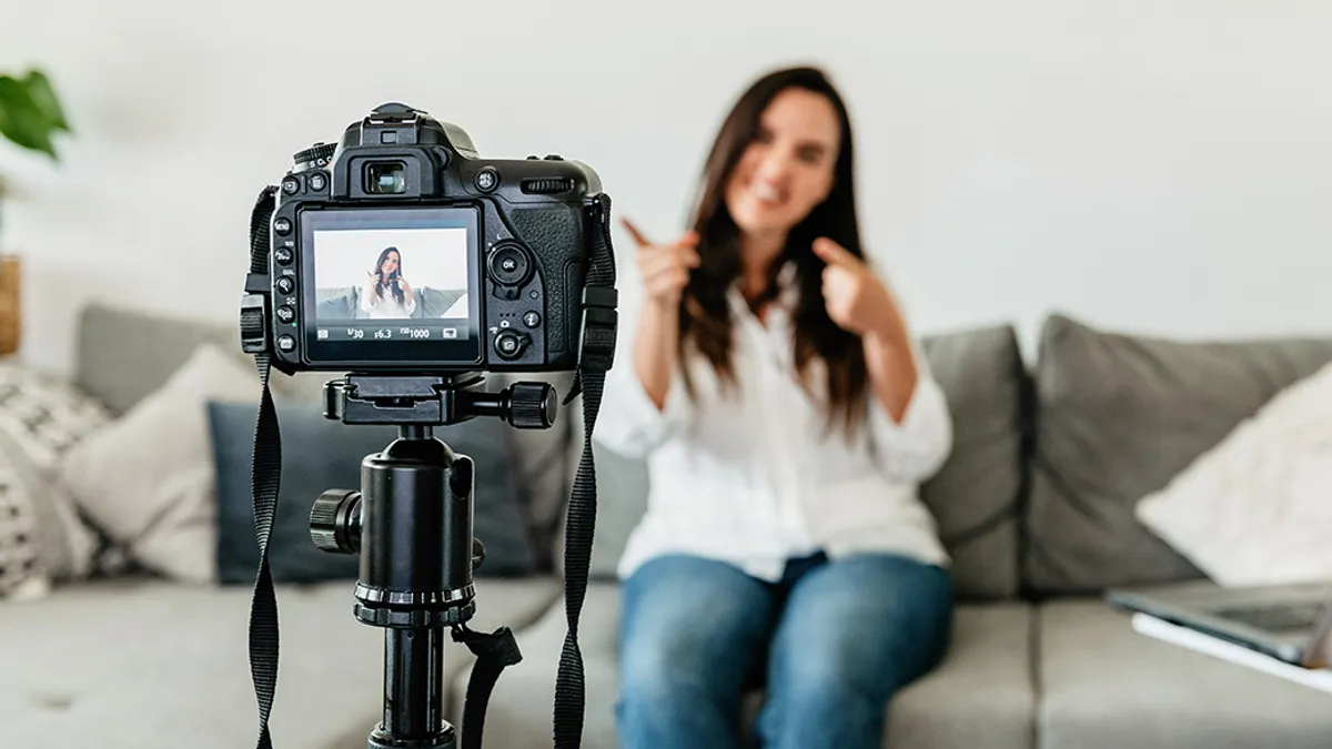 Woman seated on a couch, posing behind a digital camera