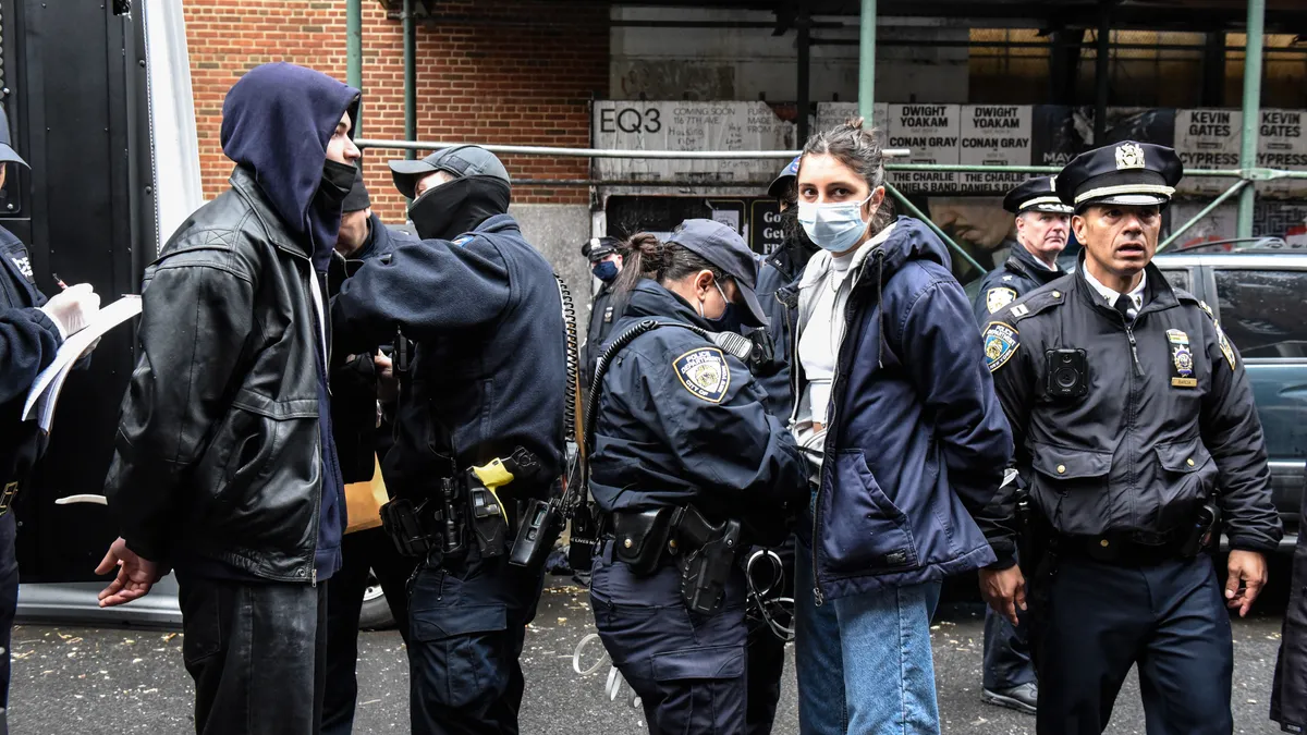 New York City police detain a resident during a homeless encampment sweep.