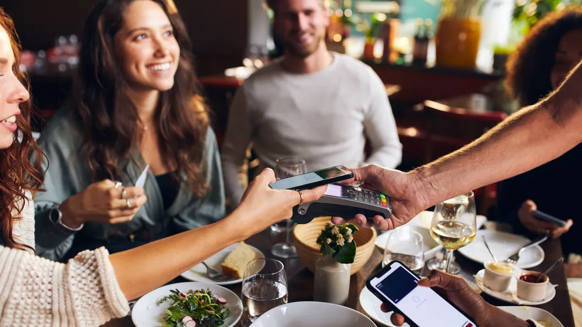 Friends paying contactlessly in restaurant