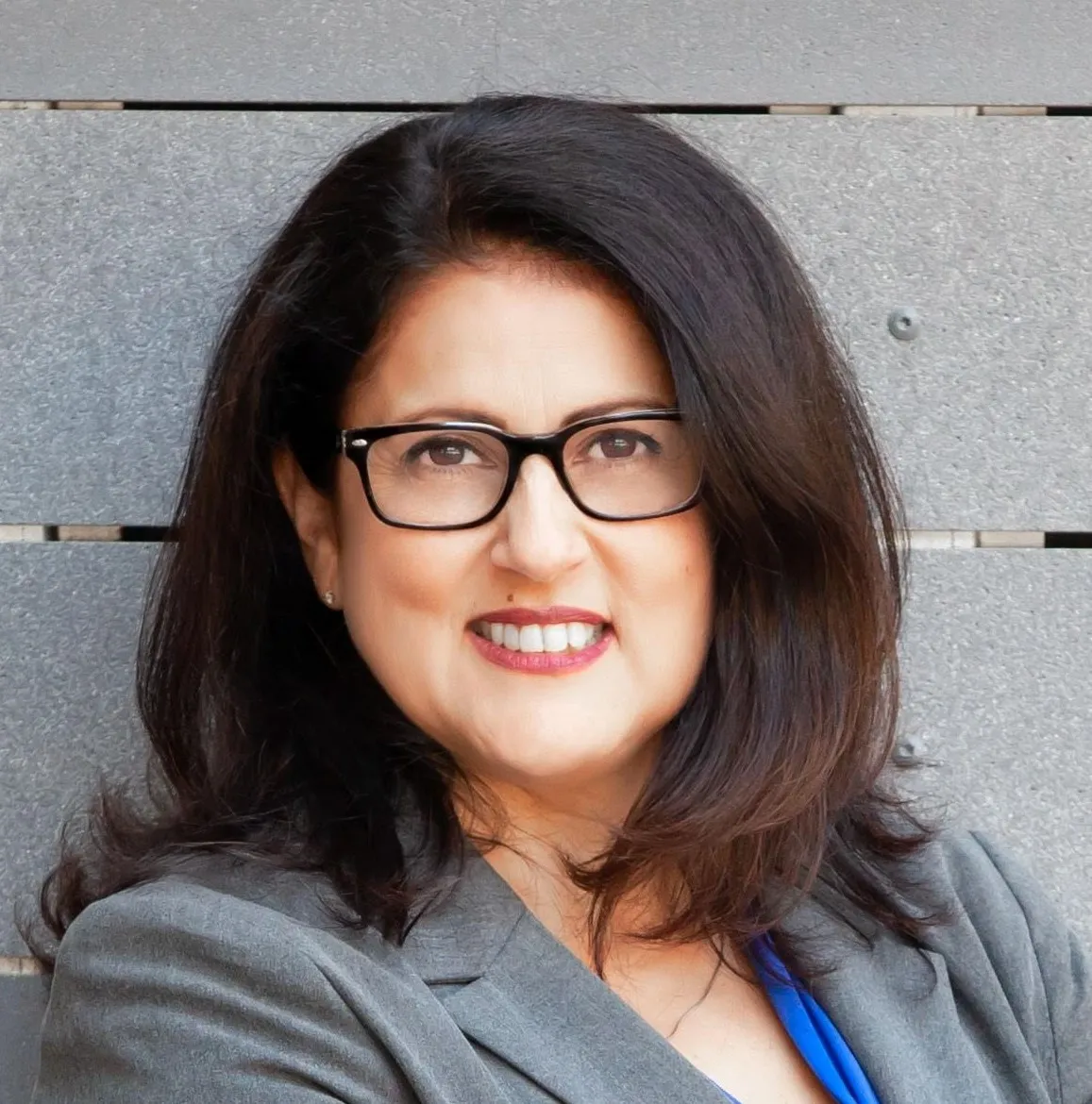 Headshot of Alva Carrasco, a Latino women with dark-framed glasses.