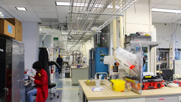 Two researchers in lab coats working in a biotechnology laboratory.