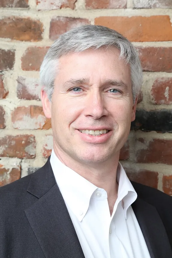 A person in a dark suit and white shirt.