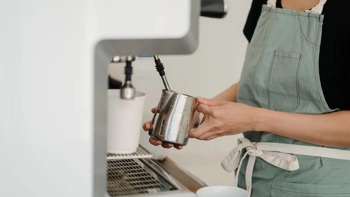 Crop coffee house worker making coffee using coffee machine