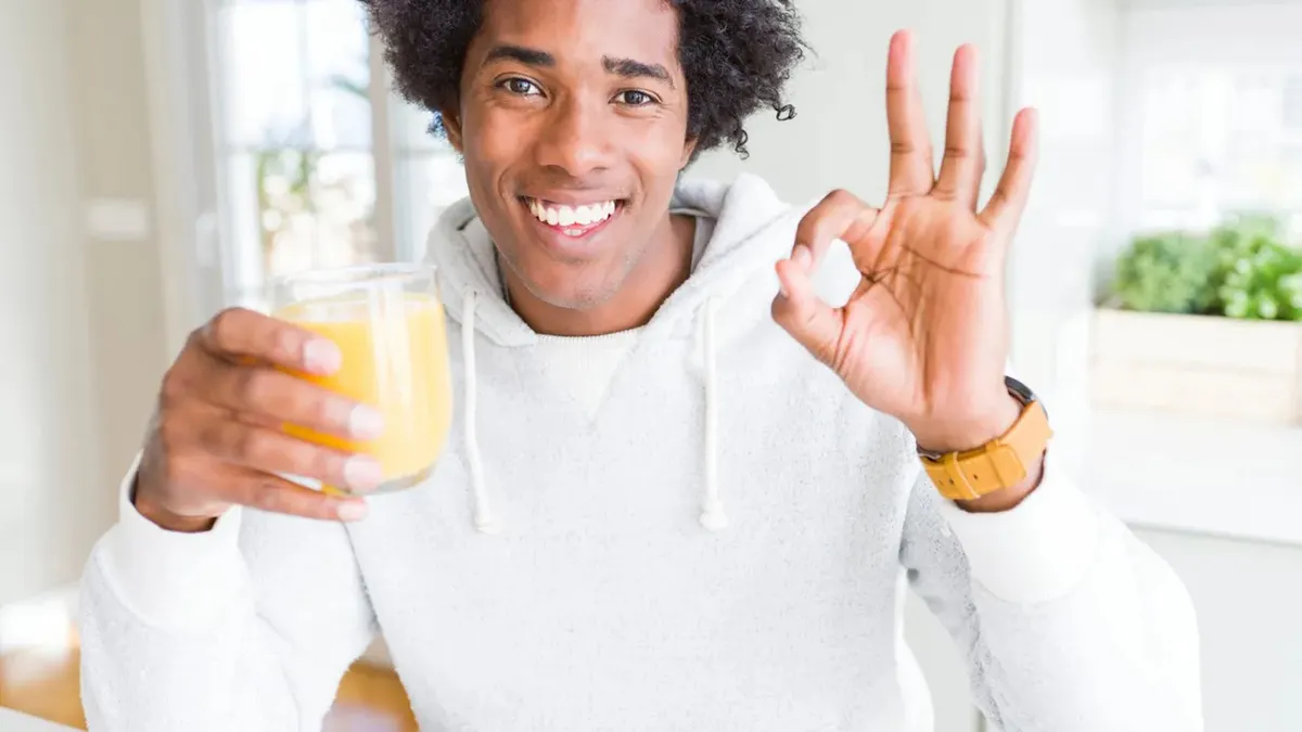 Person holding glass of orange juice