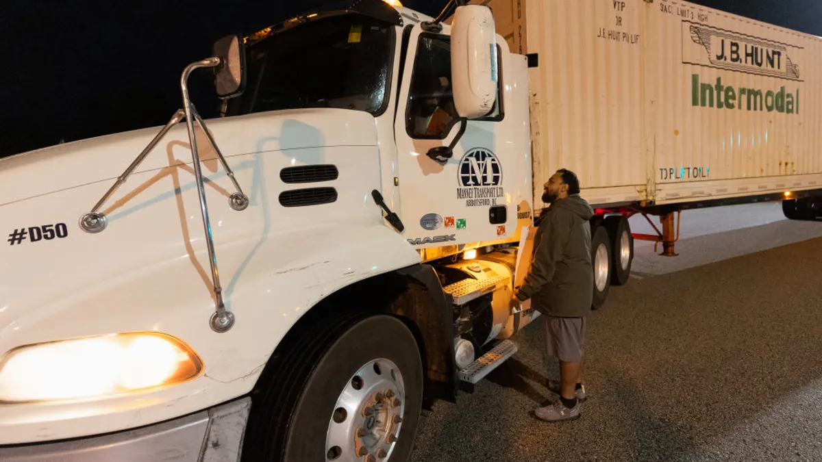 A Teamsters union member holds a picket sign while speaking to a truck driver at the entrance of CN Rail - Intermodal Yard on August 22, 2024 in Surrey, British Columbia, Canada.