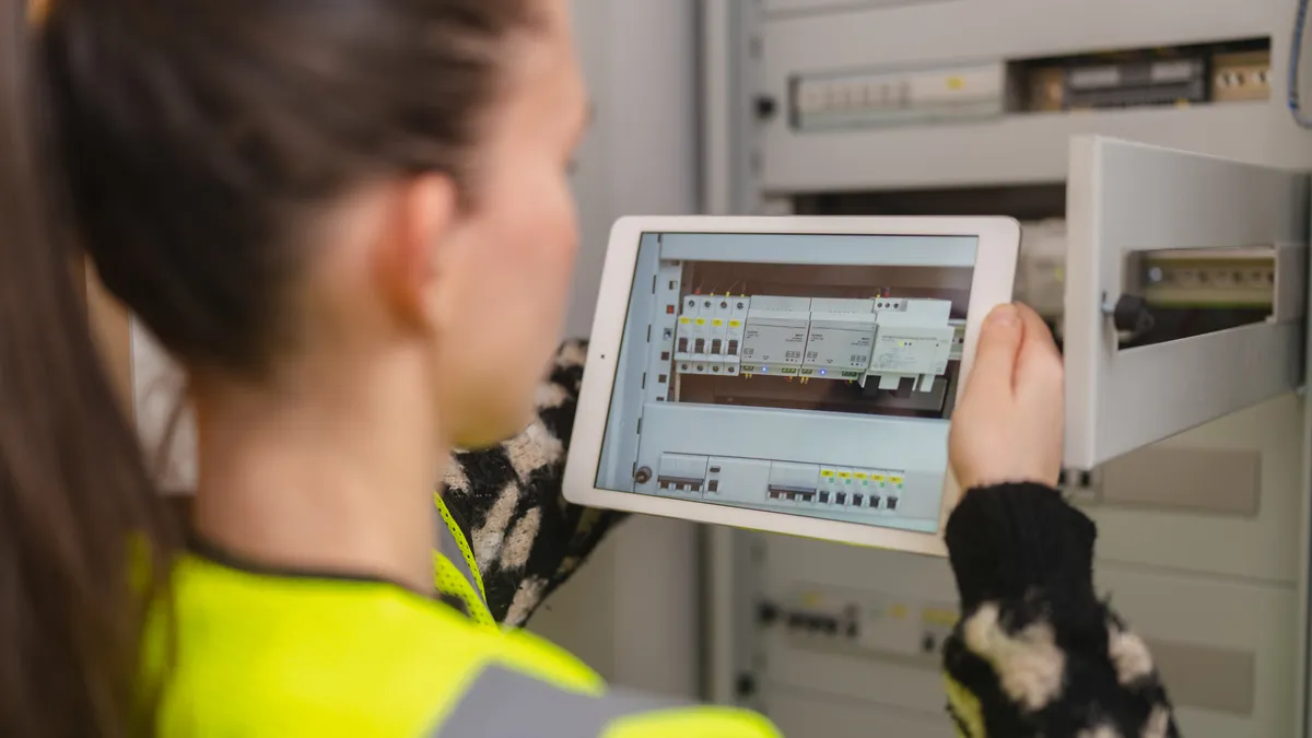 Female technician using digital tablet and fixing electric panel in home