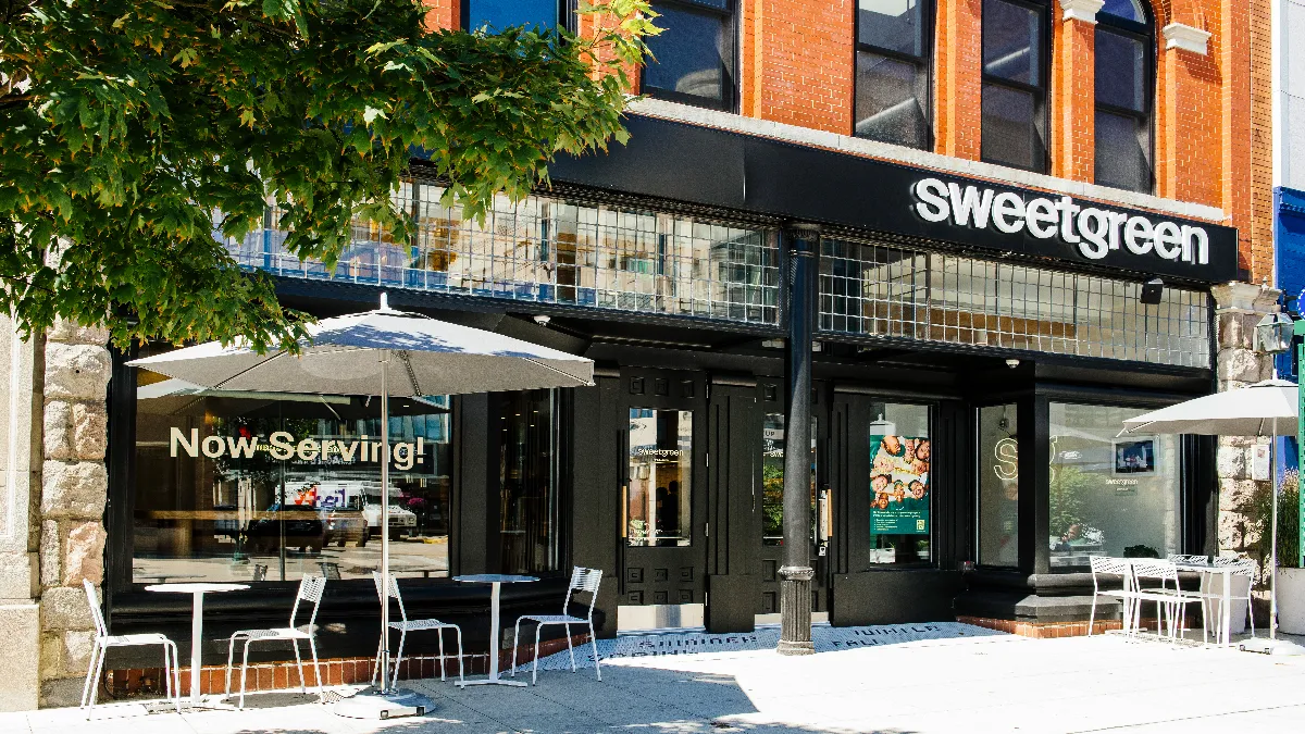 An exterior image of a restaurant with glass windows and a sign that says sweetgreen.