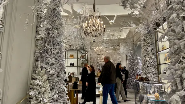 People walking around a store that is decorated for the winter holidays.