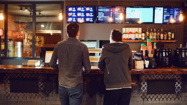 An image of two men standing at a counter ordering food.