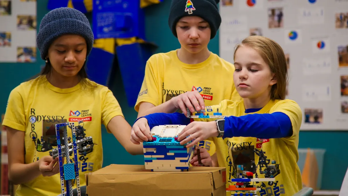Three students work on a robotics project in a room