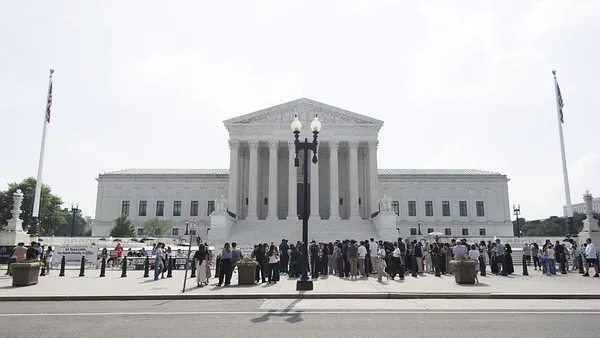 The U.S. Supreme Court Building front side is pictured with a crowd a people in front of the building.