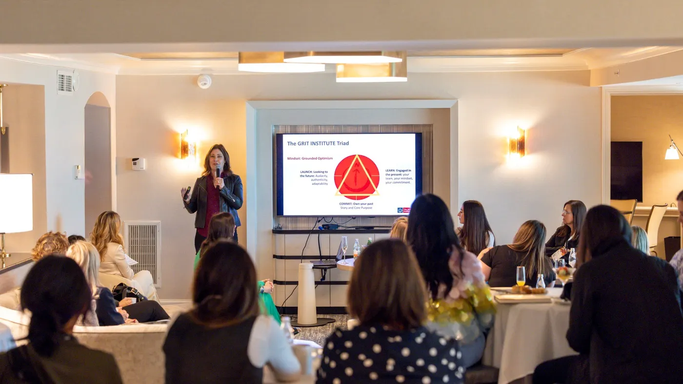 A woman stands before a group, delivering a presentation and interacting with her audience.