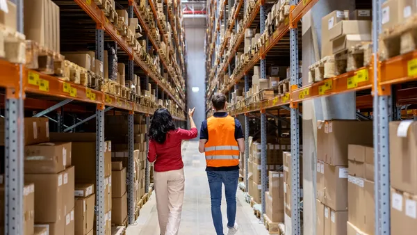 A manager and employee walk through a warehouse.