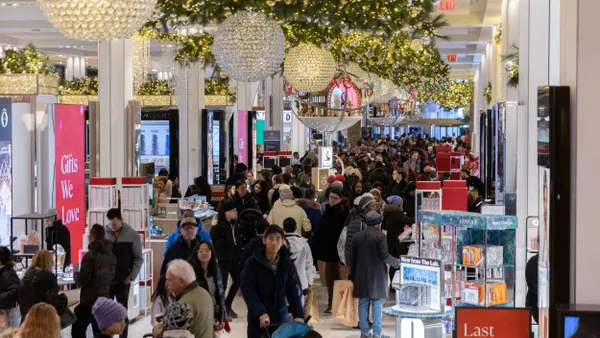 Customers move through a crowded department store with holiday decorations.