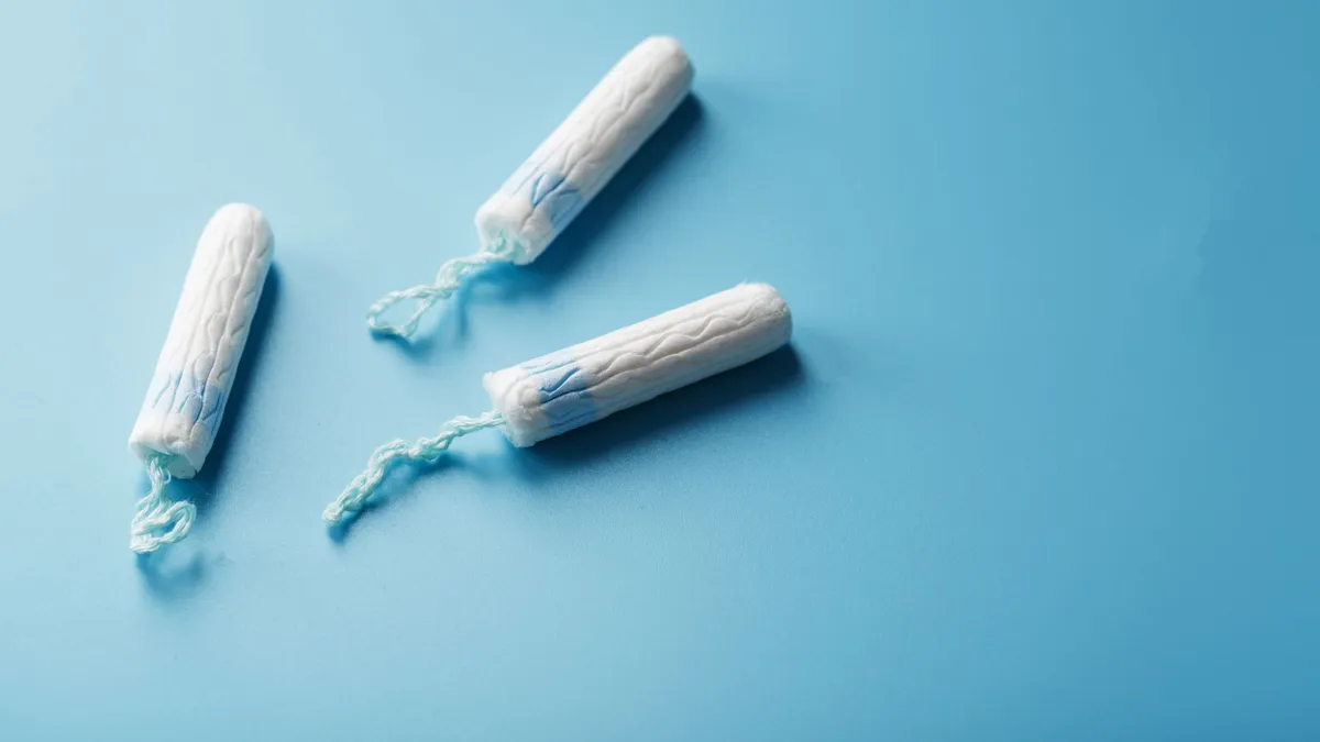 Three white gynecological tampons on a blue background.