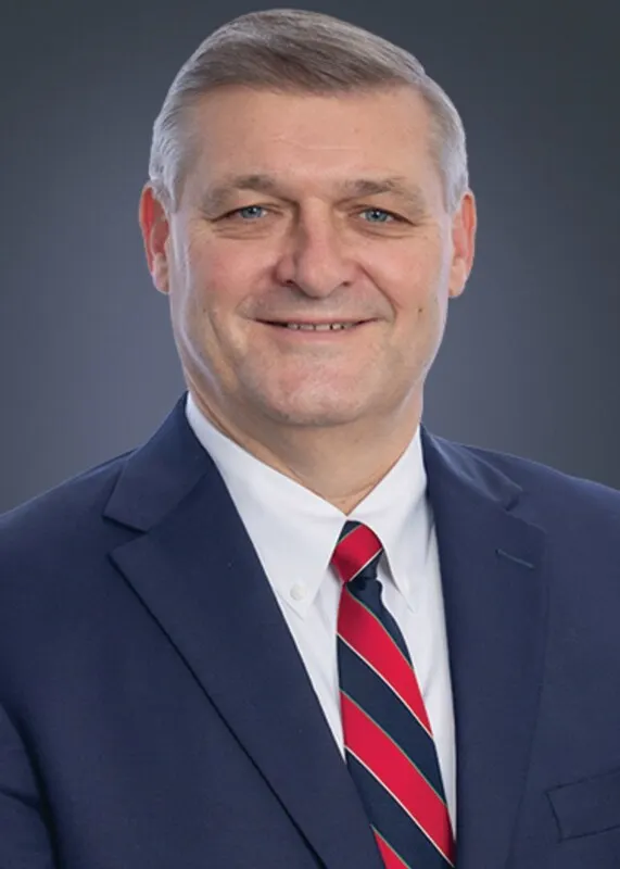 Chuck Parcher, wearing a suit and tie, poses for a photo
