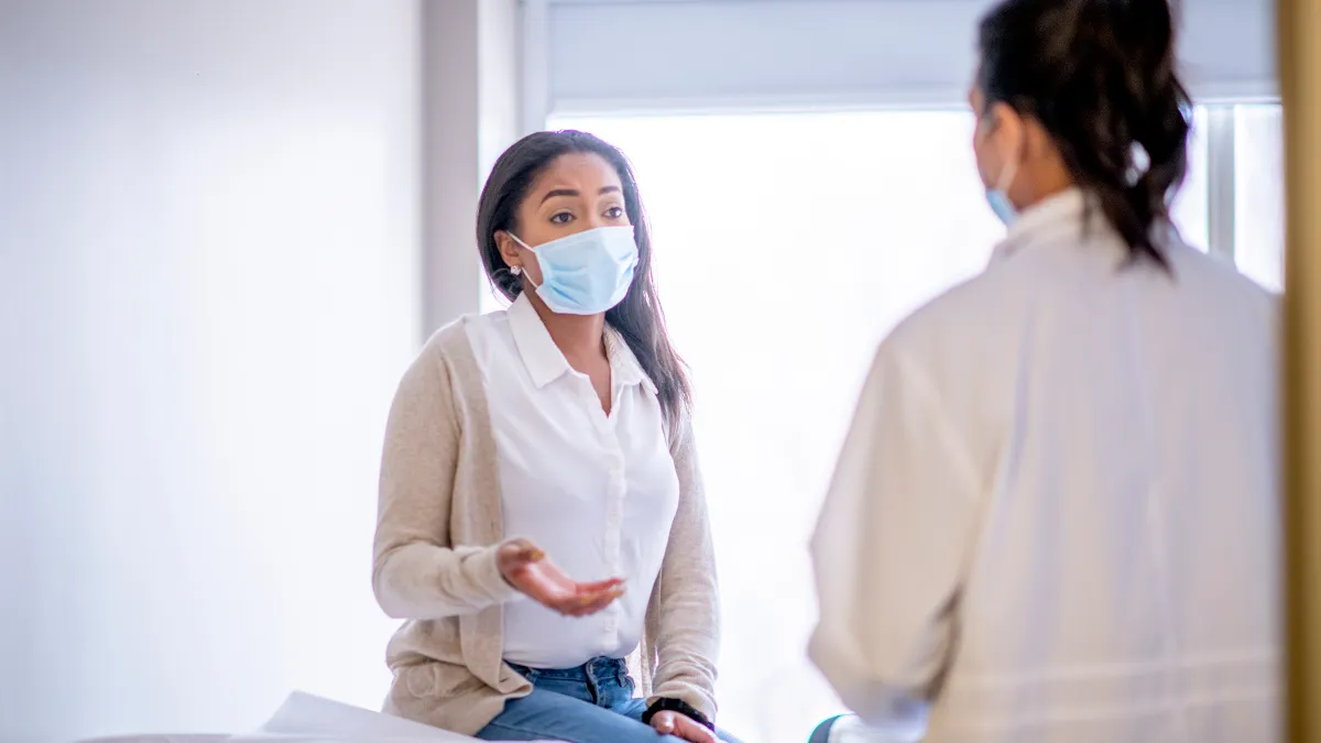 A female patient is sitting on the examination table during a medical check up with a doctor