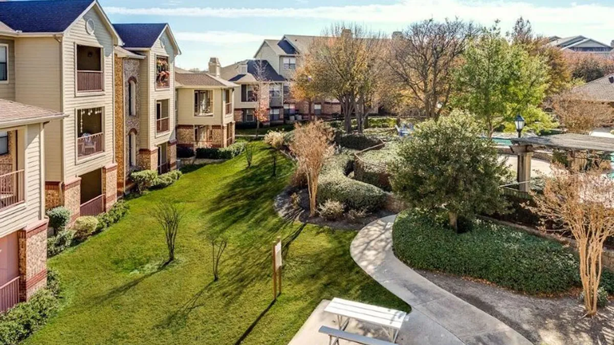 Brown apartment buildings next to grass and a sidewalk