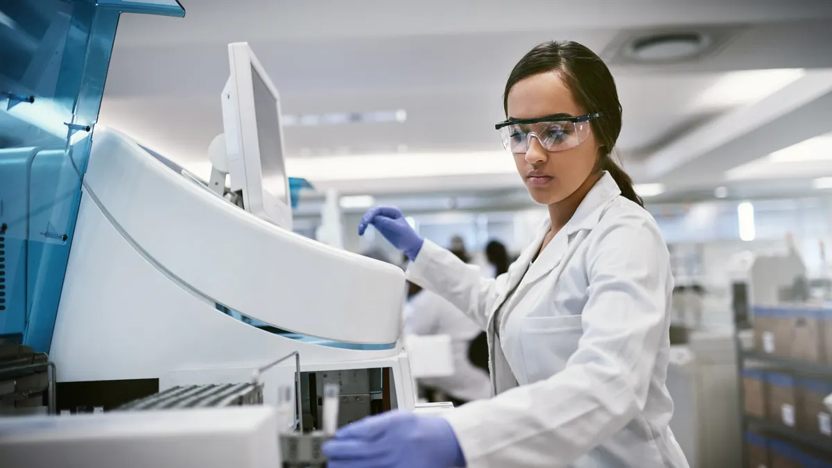 Shot of a young woman using a machine to conduct a medical test in a laboratory