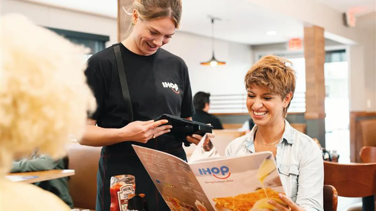 A picture of an IHOP server taking an order using a tablet.