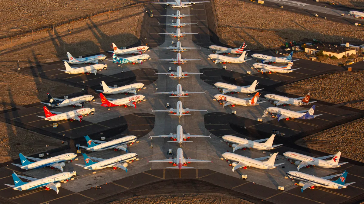 Boeing 737 MAX airplanes, along with one Boeing 787 at the top, parked at an airport as the sun rises.