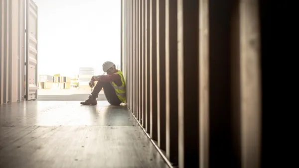 A construction worker sits sadly on a jobsite.