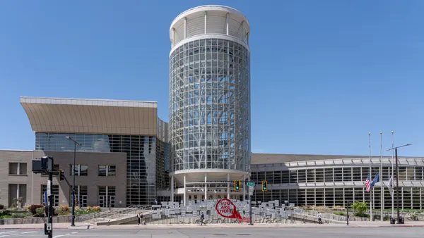 The exterior of a large convention center with a blue sky behind it.