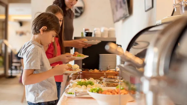 Children look at food options on a buffet.