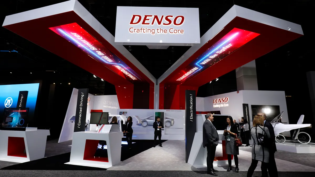 The Denso logo and booth with desks and prototypes at the North American International Auto Show