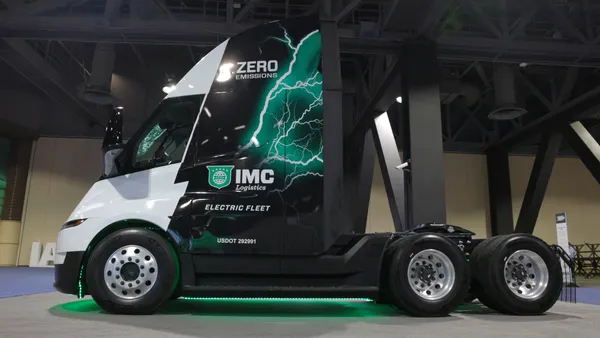 A Tesla Semi truck with IMC Logistics branding.