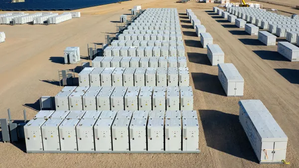 Rows of large containers sit in a dirt area.
