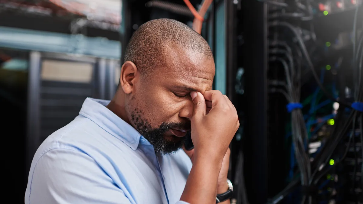 Shot of a mature man looking stressed out while working in a server room