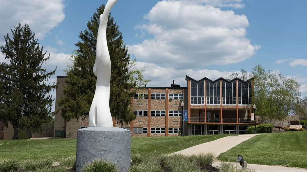 A white statute, a swirl, sits on the Alderson Broaddus University campus.