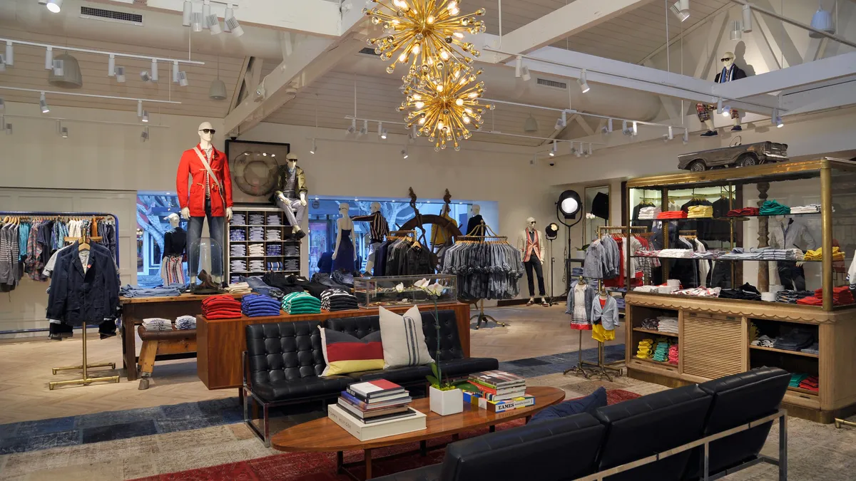 A Tommy Hilfiger store is pictured, featuring mannequins wearing clothing and shelves stocked with shirts.