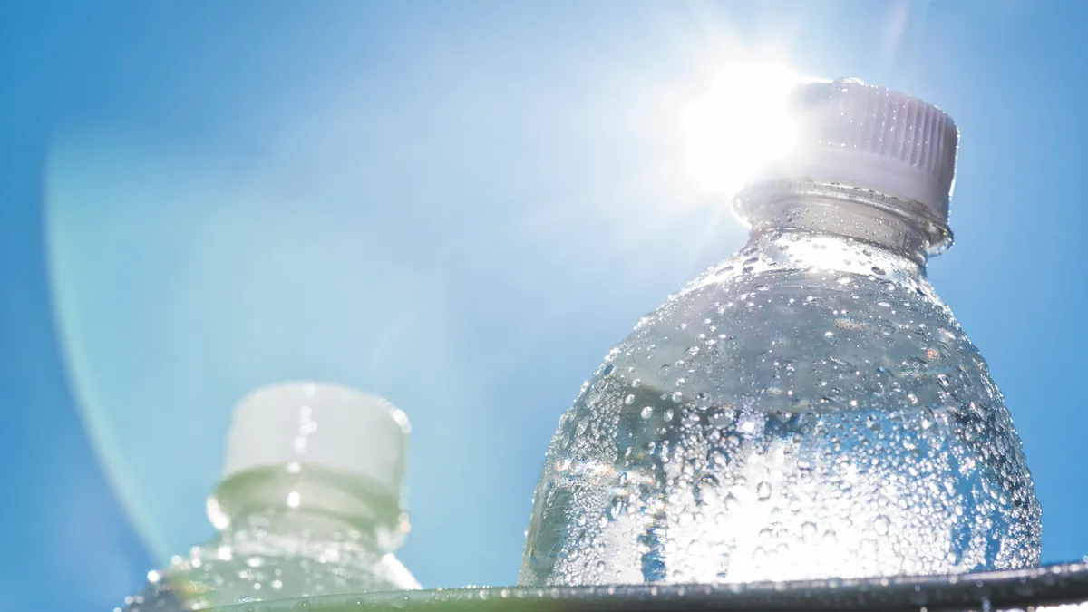 A close-up of a plastic water bottle in a bucket of ice as the Sun shines down on a hot Summer day.